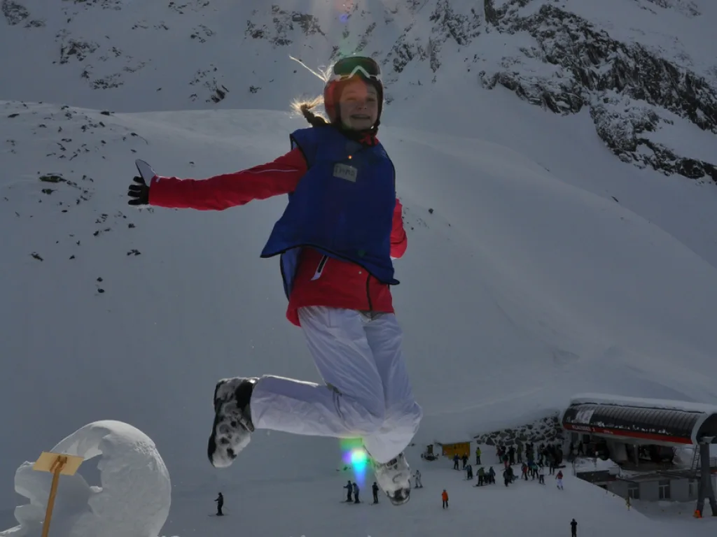 Person springt vor der Schneekulisse in die Luft.